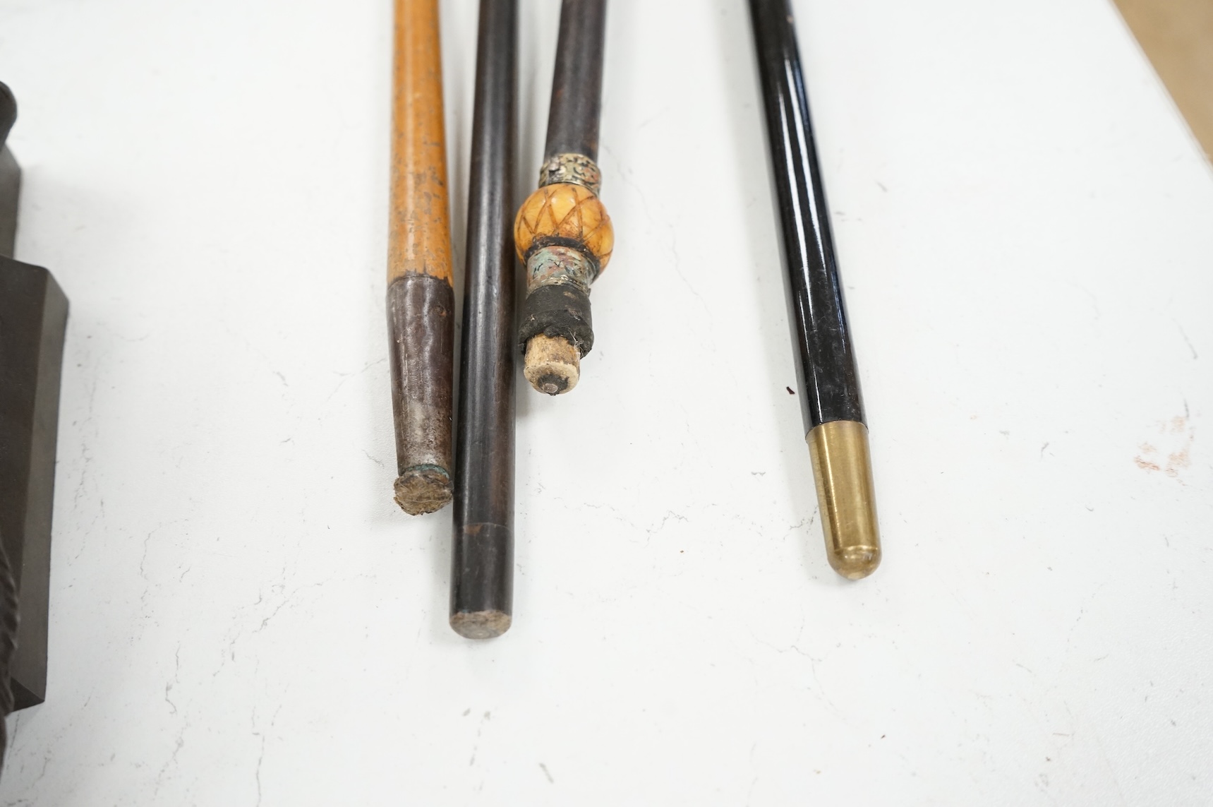 Four 19th century and later walking sticks with silver and white metal tops, to include three horse racing interest examples, largest 96cm in length